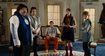 Movie still from “Idiocracy” (2006), directed by Mike Judge – A group of people standing in front of a couch; Wide shot, Low angle