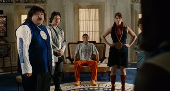 Movie still from “Idiocracy” (2006), directed by Mike Judge – A group of men and women standing in a living room; Wide shot, Low angle