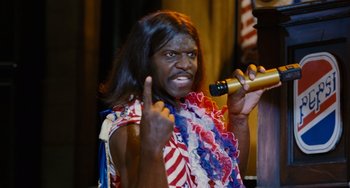 Movie still from “Idiocracy” (2006), directed by Mike Judge – A man in a costume is holding a microphone; Close Up shot, High angle