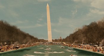Movie still from “Idiocracy” (2006), directed by Mike Judge – The washington monument stands tall in the distance as people swim in the water in front of it; Extreme Wide shot, High angle