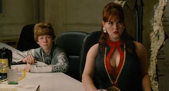 Movie still from “Idiocracy” (2006), directed by Mike Judge – A woman sitting at a table next to a boy; Medium shot, Over the shoulder angle