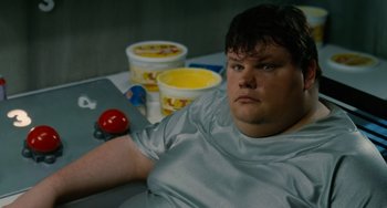 Movie still from “Idiocracy” (2006), directed by Mike Judge – A man sitting in front of two cups of ice cream; Medium shot, High angle