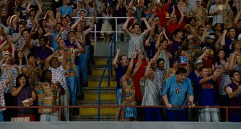 Movie still from “Idiocracy” (2006), directed by Mike Judge – A group of people standing in a stadium with their hands up; Wide shot, High angle
