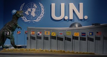 Movie still from “Idiocracy” (2006), directed by Mike Judge – A blue wall with a bunch of flags on it; Wide shot, Low angle