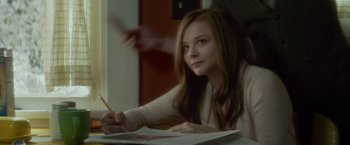 Movie still from “If I Stay” (2014), directed by R.J. Cutler – A woman sitting at a table writing on a piece of paper; Close Up shot, Over the shoulder angle