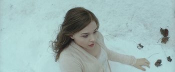 Movie still from “If I Stay” (2014), directed by R.J. Cutler – A woman sitting on the ground in the snow; Medium shot, High angle