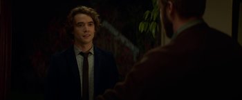 Movie still from “If I Stay” (2014), directed by R.J. Cutler – A man in a suit and tie looking at himself in a mirror; Medium shot, Over the shoulder angle