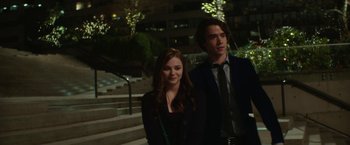 Movie still from “If I Stay” (2014), directed by R.J. Cutler – A man and a woman standing next to each other in front of stairs; Medium shot, Over the shoulder angle