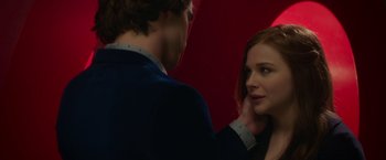 Movie still from “If I Stay” (2014), directed by R.J. Cutler – A man and a woman looking at one another in front of a red wall; Close Up shot, Over the shoulder angle