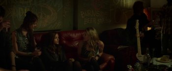 Movie still from “If I Stay” (2014), directed by R.J. Cutler – Two women sitting on a red couch in a room; Medium shot, Over the shoulder angle