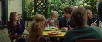 Movie still from “If I Stay” (2014), directed by R.J. Cutler – A group of people sitting around a table eating; Medium shot, Over the shoulder angle