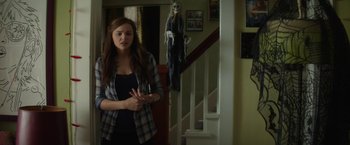 Movie still from “If I Stay” (2014), directed by R.J. Cutler – A woman standing in front of a staircase next to a skeleton; Medium shot, Over the shoulder angle