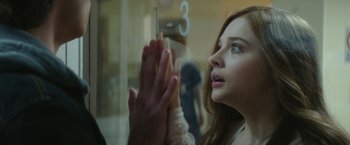 Movie still from “If I Stay” (2014), directed by R.J. Cutler – A woman is looking out a window at a person; Close Up shot, Over the shoulder angle