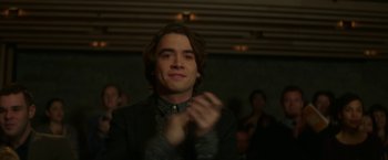 Movie still from “If I Stay” (2014), directed by R.J. Cutler – A man in a suit claps his hands in front of a crowd of onlookers; Close Up shot, Over the shoulder angle