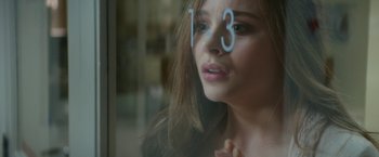 Movie still from “If I Stay” (2014), directed by R.J. Cutler – A woman with a number on her face looking out a window; Close Up shot, Over the shoulder angle