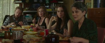 Movie still from “If I Stay” (2014), directed by R.J. Cutler – A group of people sitting at a table eating food; Medium shot, Over the shoulder angle