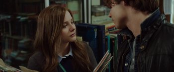 Movie still from “If I Stay” (2014), directed by R.J. Cutler – A girl and a boy are looking at each other in a library; Close Up shot, Over the shoulder angle