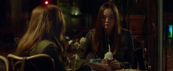 Movie still from “If I Stay” (2014), directed by R.J. Cutler – Two women are sitting at a table and one of the women is holding a cell phone; Medium shot, Over the shoulder angle