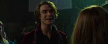 Movie still from “If I Stay” (2014), directed by R.J. Cutler – A man with long hair is smiling for the camera; Close Up shot, Over the shoulder angle