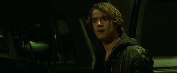 Movie still from “If I Stay” (2014), directed by R.J. Cutler – A man with long brown hair stares into the camera; Close Up shot, Over the shoulder angle