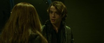 Movie still from “If I Stay” (2014), directed by R.J. Cutler – A young man with long hair and a black jacket is talking to a young woman; Close Up shot, Over the shoulder angle