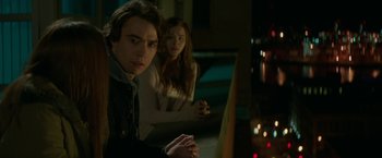 Movie still from “If I Stay” (2014), directed by R.J. Cutler – A man and a woman are looking at a television; Medium shot, Over the shoulder angle