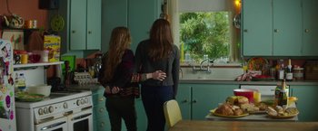 Movie still from “If I Stay” (2014), directed by R.J. Cutler – Two young women are standing in a kitchen looking out the window; Medium shot, Over the shoulder angle