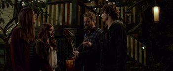 Movie still from “If I Stay” (2014), directed by R.J. Cutler – A group of people standing next to each other holding instruments; Medium shot, Over the shoulder angle