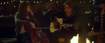 Movie still from “If I Stay” (2014), directed by R.J. Cutler – A group of people sitting in a room playing instruments; Medium shot, Over the shoulder angle