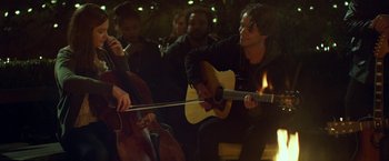 Movie still from “If I Stay” (2014), directed by R.J. Cutler – A group of people sitting in a room playing instruments; Medium shot, Over the shoulder angle