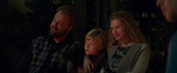 Movie still from “If I Stay” (2014), directed by R.J. Cutler – A man and a woman and a child are sitting together; Medium shot, Over the shoulder angle