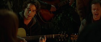 Movie still from “If I Stay” (2014), directed by R.J. Cutler – A man playing a guitar while another man plays a guitar; Medium shot, Over the shoulder angle