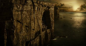 Movie still from “Immortals” (2011), directed by Tarsem Singh – A large rock formation near the ocean at sunset; Extreme Wide shot, High angle