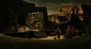 Movie still from “Immortals” (2011), directed by Tarsem Singh – A stage set with people and rocks in the background; Extreme Wide shot, High angle