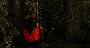 Movie still from “Immortals” (2011), directed by Tarsem Singh – A person with a red cape standing in front of a waterfall; Extreme Wide shot, High angle