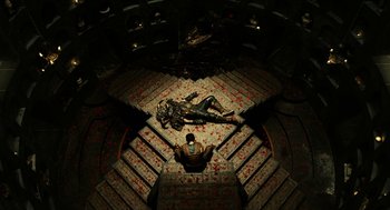 Movie still from “Immortals” (2011), directed by Tarsem Singh – A man laying on the ground next to a dead body; Extreme Wide shot, Overhead angle