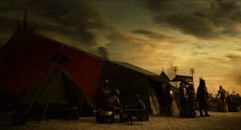 Movie still from “Immortals” (2011), directed by Tarsem Singh – A group of people sitting around a tent on the beach; Extreme Wide shot, Low angle