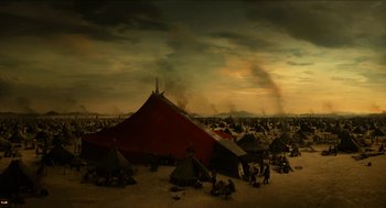 Movie still from “Immortals” (2011), directed by Tarsem Singh – A group of people sitting around tents in the desert; Extreme Wide shot, High angle