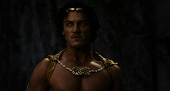 Movie still from “Immortals” (2011), directed by Tarsem Singh – A man with a gold chain around his neck; Medium shot, Over the shoulder angle