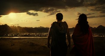 Movie still from “Immortals” (2011), directed by Tarsem Singh – Two people are walking on the beach at sunset; Extreme Wide shot, Low angle
