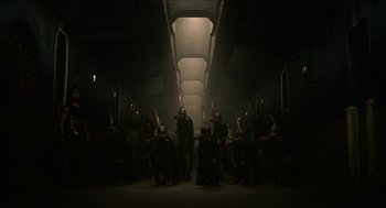 Movie still from “Immortals” (2011), directed by Tarsem Singh – A group of people standing in a dark room; Wide shot, High angle