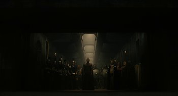 Movie still from “Immortals” (2011), directed by Tarsem Singh – A group of people standing in a dark room; Wide shot, Low angle