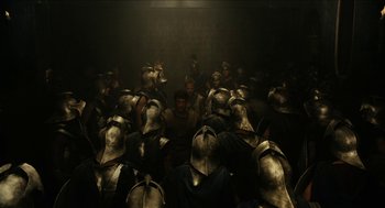 Movie still from “Immortals” (2011), directed by Tarsem Singh – A group of men in metal helmets in a dark room; Wide shot, High angle