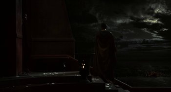 Movie still from “Immortals” (2011), directed by Tarsem Singh – A man in a cape standing next to a black cat; Extreme Wide shot, Low angle