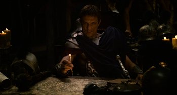 Movie still from “Immortals” (2011), directed by Tarsem Singh – A man dressed in roman clothes lighting a candle; Medium shot, High angle