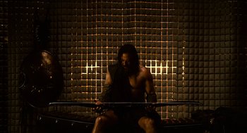 Movie still from “Immortals” (2011), directed by Tarsem Singh – A man sitting on a bench in front of a brick wall; Medium shot, High angle