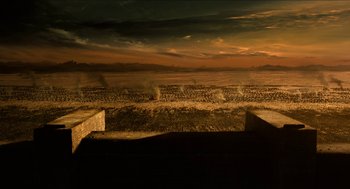 Movie still from “Immortals” (2011), directed by Tarsem Singh – A view of a desert landscape at sunset with smoke coming out of the sky; Extreme Wide shot, High angle