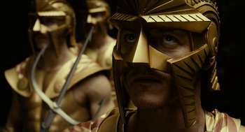 Movie still from “Immortals” (2011), directed by Tarsem Singh – A man wearing a gold helmet; Close Up shot, Over the shoulder angle