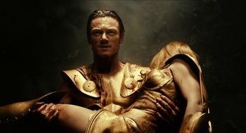 Movie still from “Immortals” (2011), directed by Tarsem Singh – A man and a woman dressed in gold with blood on them; Medium shot, High angle