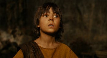 Movie still from “Immortals” (2011), directed by Tarsem Singh – A young boy wearing a brown and yellow shirt looking up; Close Up shot, Low angle